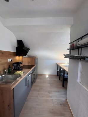 Une cuisine moderne avec des meubles en bois, un évier en acier inoxydable, une machine à café et un four encastré.