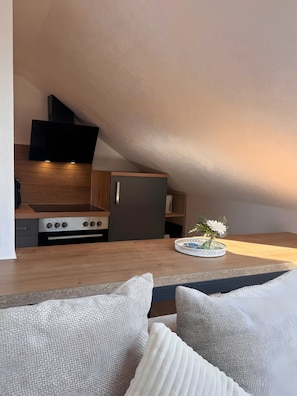 Une cuisine moderne dotée d’un four et d’un micro-ondes encastrés, d’un plan de travail en bois et d’un petit coin repas avec une table et des chaises.