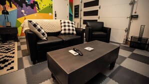 A room with a black leather sofa, a black armchair, and a small table with a remote control. - Studio with AC in charming Seattle neighborhood (Seattle)