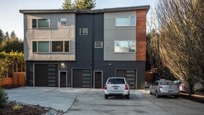 A modern two-story building with a garage, a driveway, and two parked cars. - Studio with AC in charming Seattle neighborhood (Seattle)