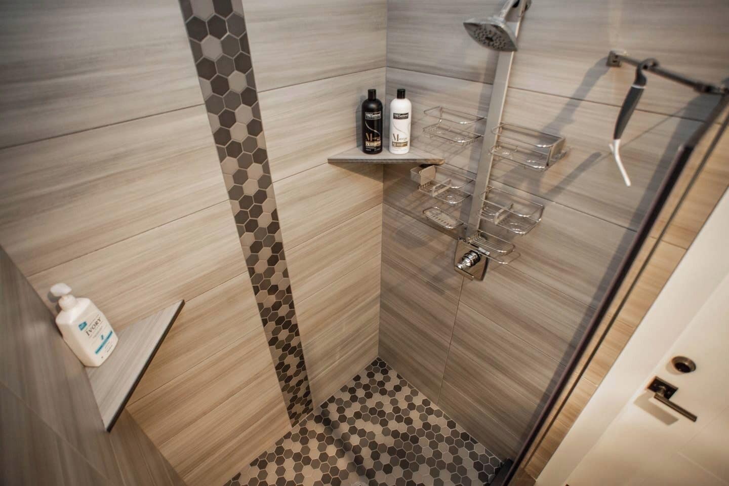 A modern shower area with a glass door, a showerhead, and a shelf with toiletries.. Studio with AC in charming Seattle neighborhood
