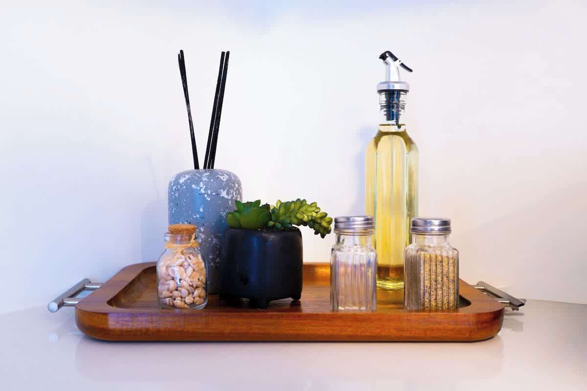 Un plateau contenant divers récipients, notamment un bocal bleu, un pot noir avec une plante, une bouteille jaune et deux bouteilles en verre transparent.
