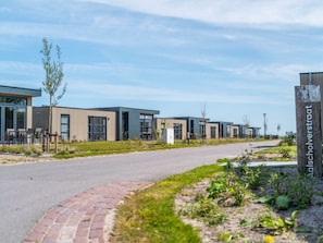 A row of modern buildings with large windows, a paved pathway, and a sign indicating the name of the location.