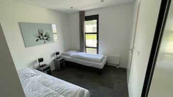 Quarto moderno com duas camas, uma escrivaninha, uma cadeira e uma janela com cortinas.