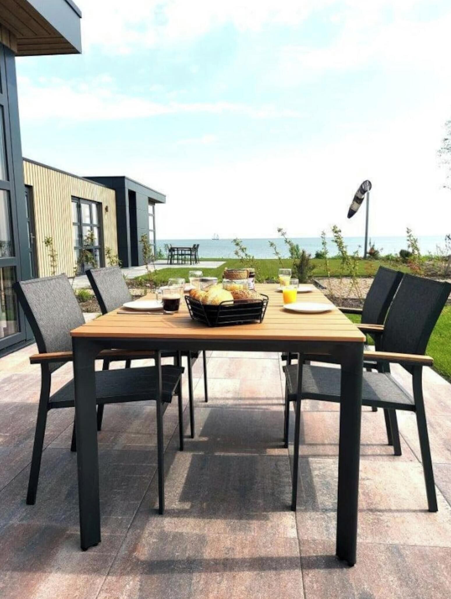 An outdoor dining area with a table set for two, overlooking a body of water.