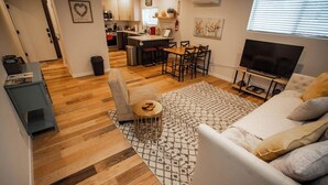 Een moderne woonkamer met een bank, televisie en een eethoek met stoelen en een tafel.