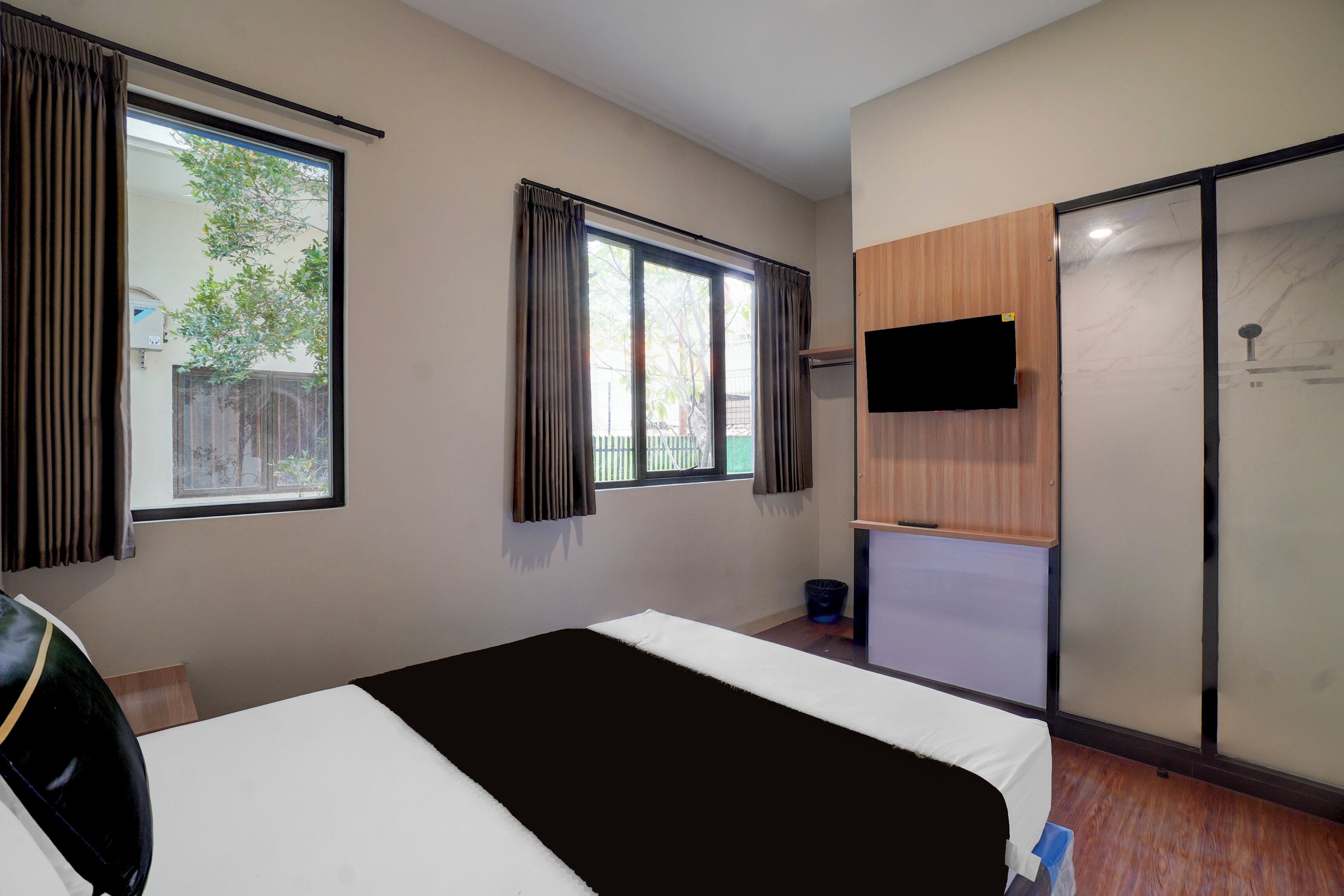 Habitación de hotel con cama, televisión montada en la pared y puerta corrediza hacia la zona de la ducha.