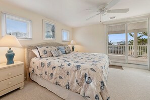 Ein Schlafzimmer mit einem Bett, zwei Nachttischen, einem Deckenventilator und einem Balkon mit Geländer.