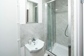 Ein Badezimmer mit Waschbecken, Spiegel und Duschkabine.
