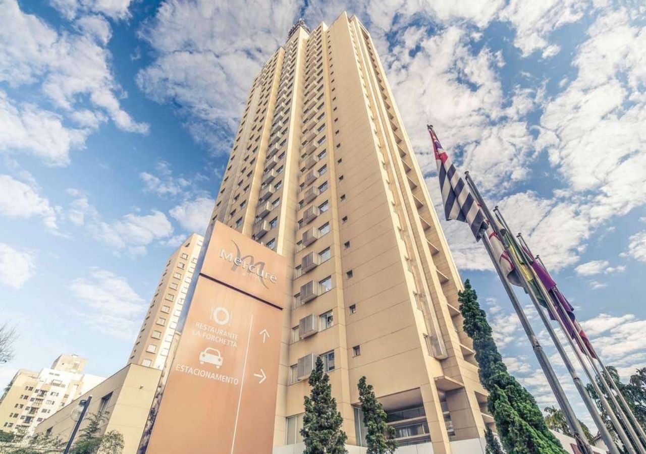 Un grand hôtel à plusieurs étages, une enseigne indiquant la présence d’un restaurant et d’un parking, et plusieurs drapeaux.