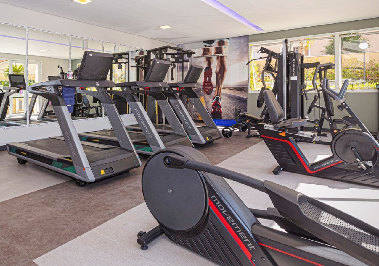 Une salle de sport équipée de tapis de course, d’appareils de musculation et dotée d’une grande fenêtre.