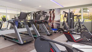 Ein Fitnessstudio mit Laufbändern, Kraftgeräten und einem großen Fenster.