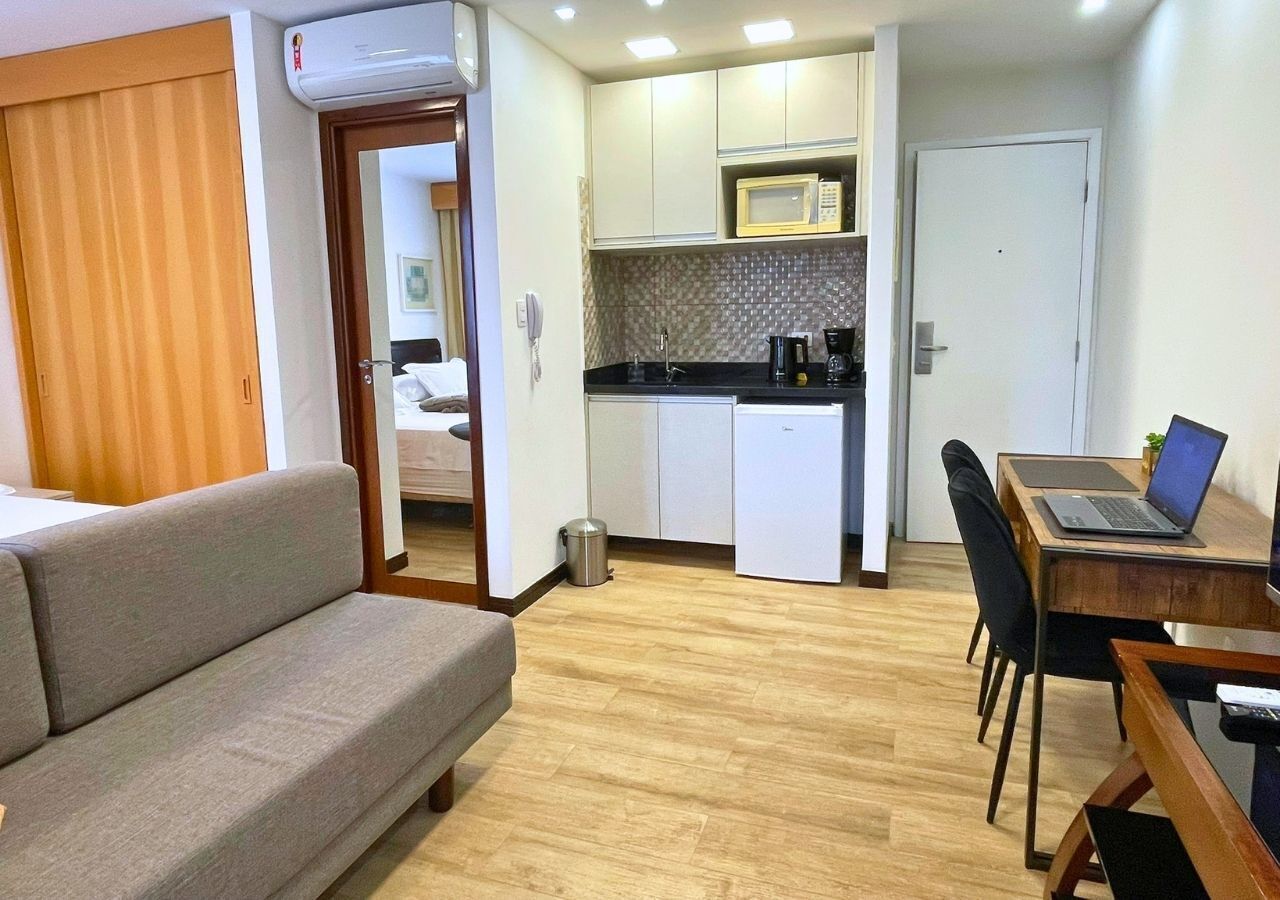 Un espace de vie compact comprenant un canapé, une table à manger avec des chaises, une kitchenette équipée d’un four à micro-ondes et une porte donnant sur une autre pièce.