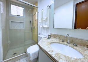 A bathroom with a glass-enclosed shower, a sink with a marble countertop, and a mirror above the sink. - Modern apartment in Vila Olímpia near Av. Faria Lima with a pool and fitness center (São Paulo)