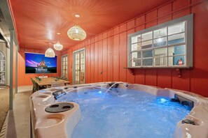 Een jacuzzi met waterstralen, een televisie waarop een Disneyfilm draait, en een houten tafel met stoelen.