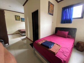 A bedroom with a bed, a door, a window with blue curtains, and a wall with two framed pictures. - Hotel O near City of Tomorrow Mall forme (Surabaya)