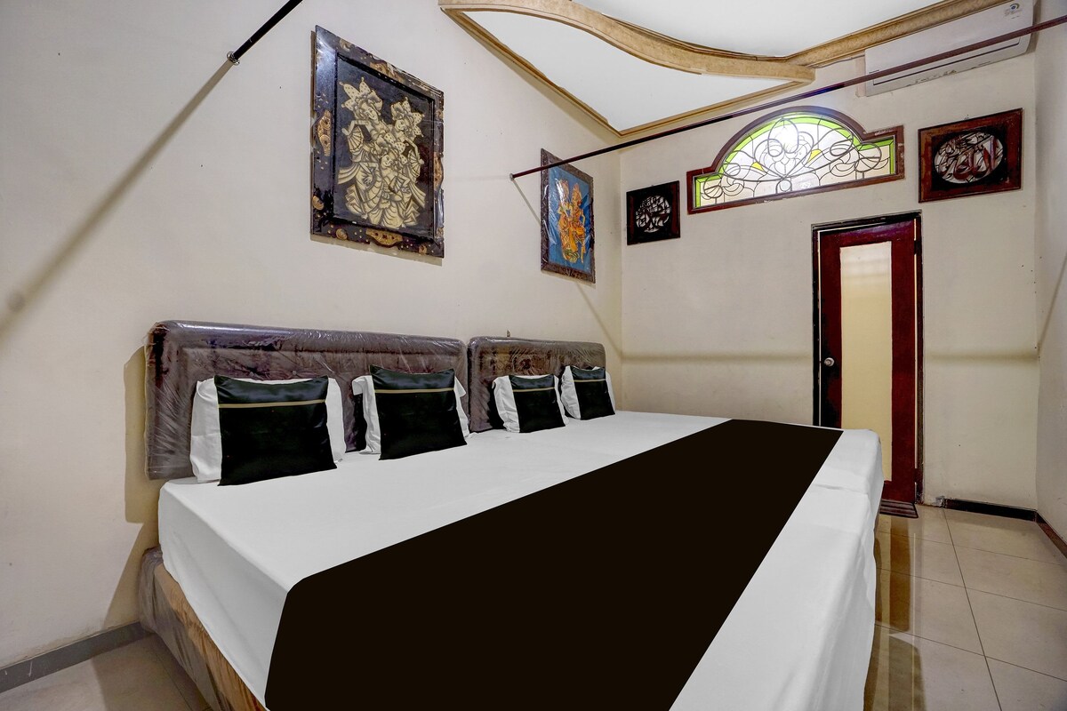 A bedroom with a bed, pillows, a headboard, a door, and wall decorations.