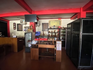 A room with a wooden counter, a refrigerator, shelves with pottery, and a television mounted on the wall. - Hotel O near City of Tomorrow Mall forme (Surabaya)