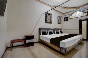 Quarto com cama, mesa de cabeceira, prateleira na parede e porta.