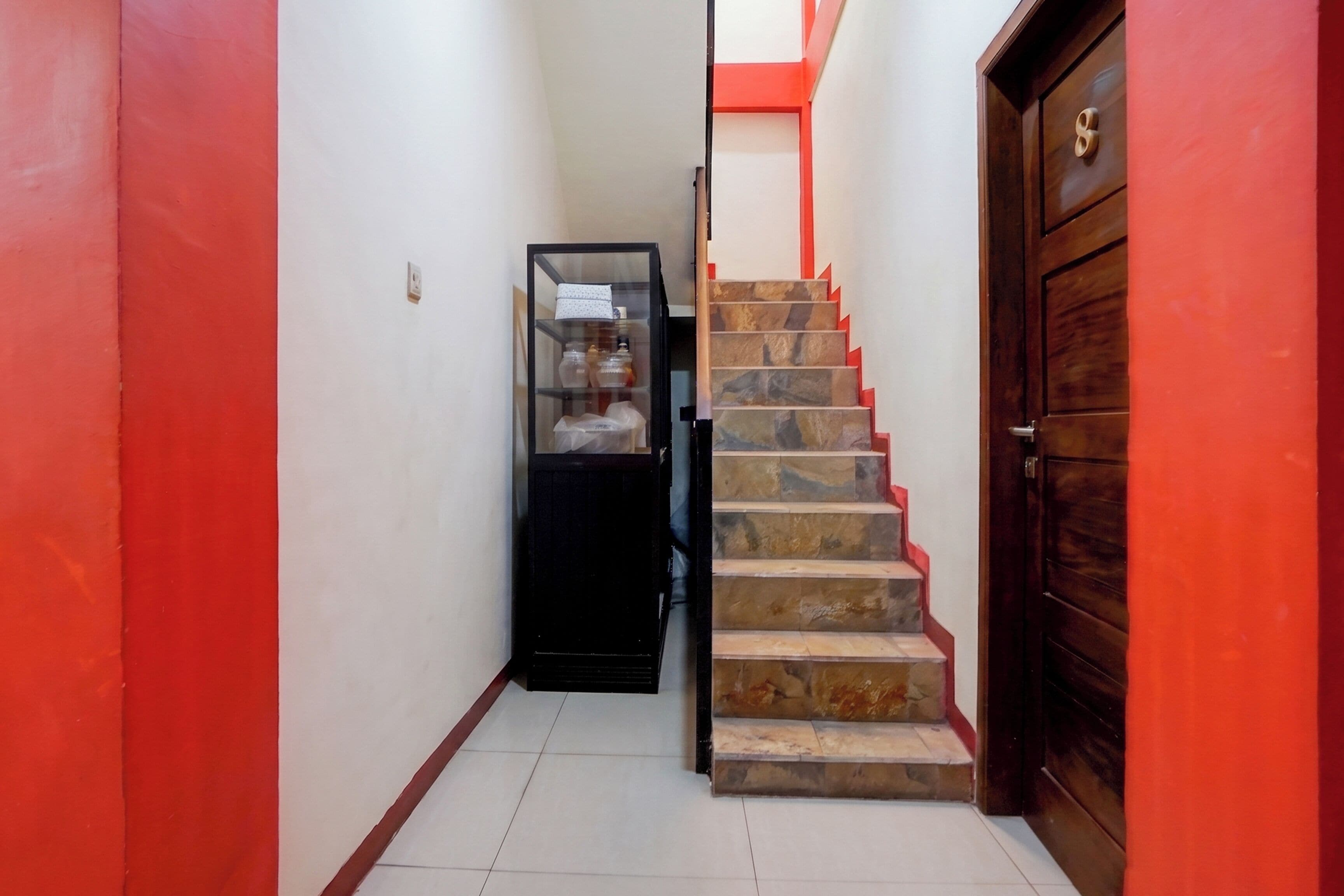 A narrow hallway with a staircase leading to a door with a brass handle.