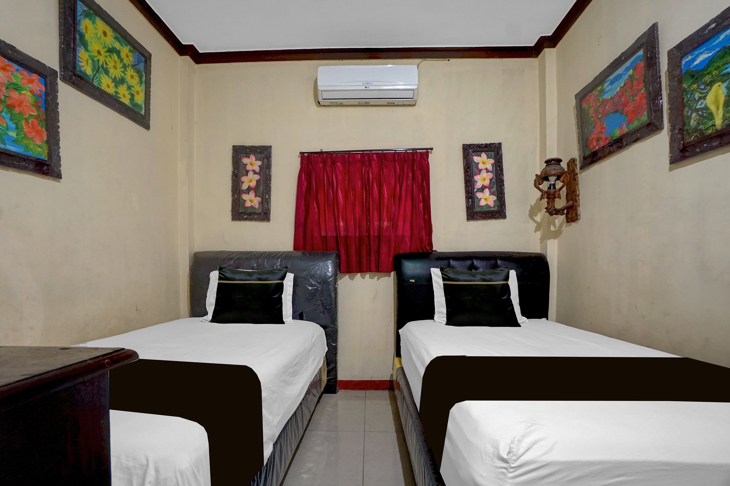 A room with two beds, a red curtain, and wall-mounted air conditioning.
