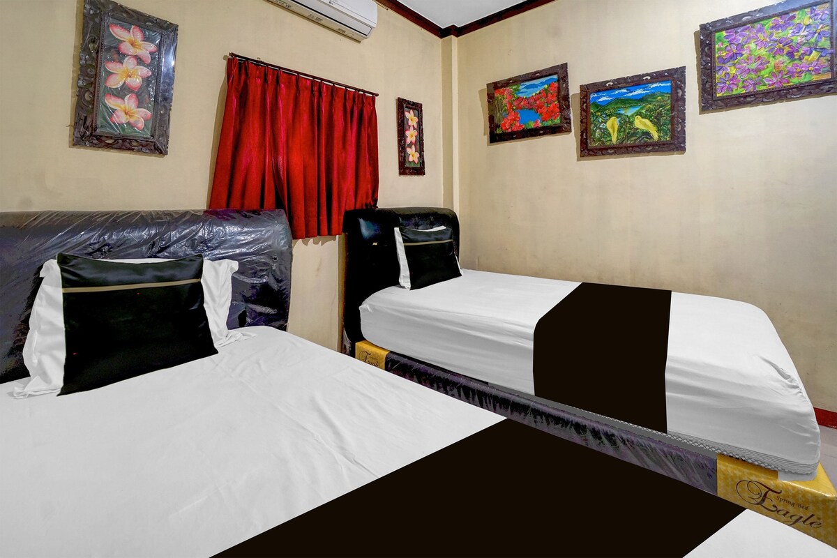 A hotel room with two beds, a red curtain, and three framed artworks on the walls.