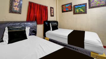 A hotel room with two beds, a red curtain, and three framed artworks on the walls.