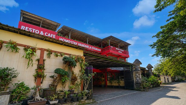 A building with a red sign reading 'RESTO & CAFE HOMESTAY VANDHELA SYARIAH' and a covered entrance.
