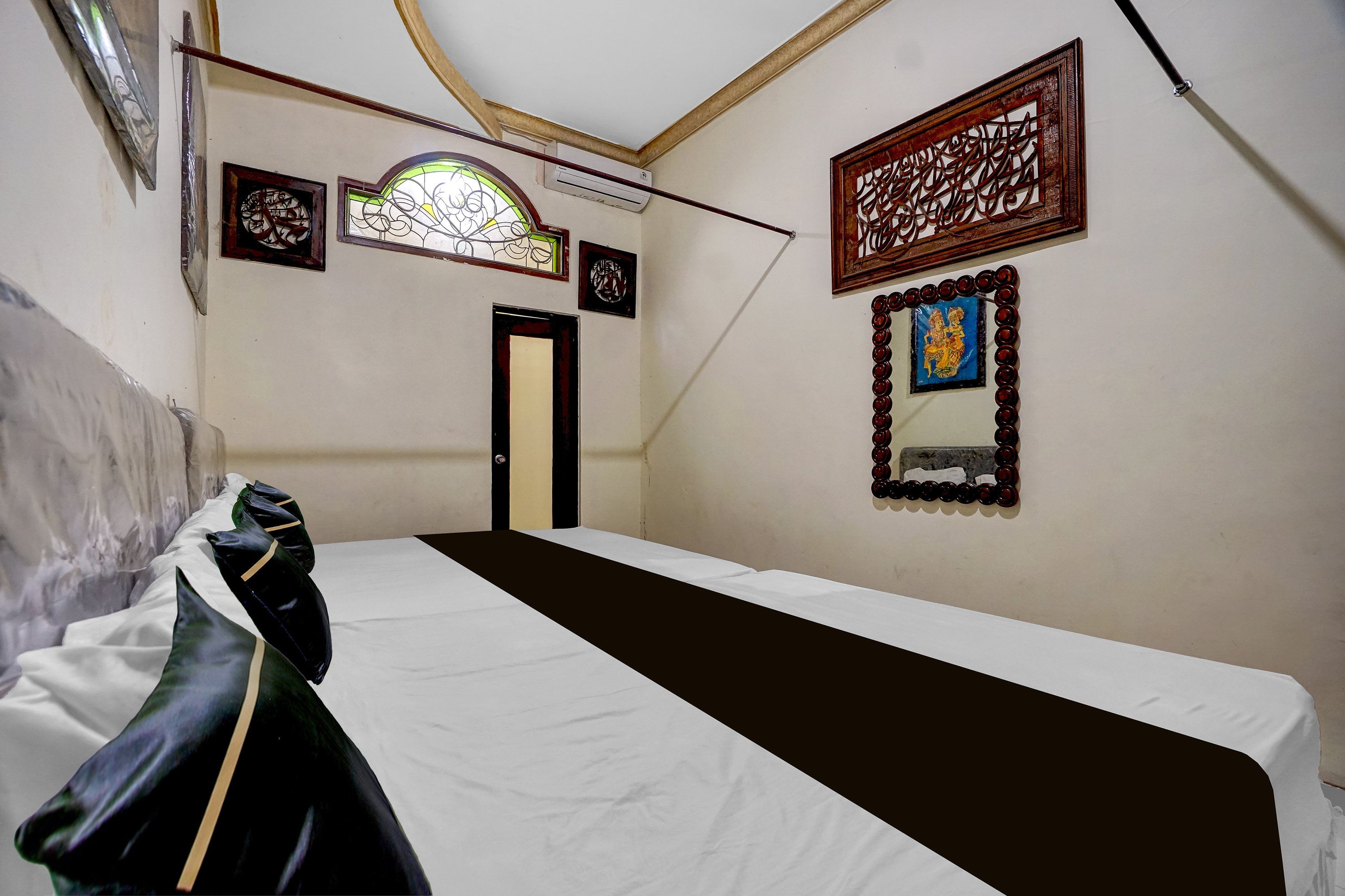 Ein Zimmer mit einem Bett, einer Tür und einer Wand mit gerahmten Kunstwerken.