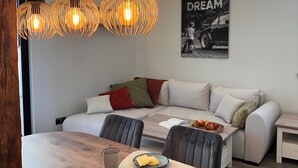 Een moderne eetruimte met een houten tafel, twee hanglampen en een poster aan de muur.