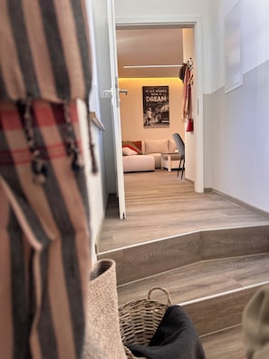 A hallway leading to a living area with a sofa, a poster, and a coat rack. - Historic downtown apartment with a game room, air conditioning, and a balcony in Torgau (Torgau)