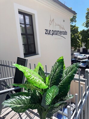 A building with a sign reading 'zur promenade apartment' and a large green plant in the foreground. - Historic downtown apartment with a game room, air conditioning, and a balcony in Torgau (Torgau)