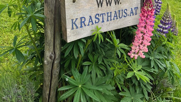 Un senyal de fusta amb el text 'KRASTHAUS' i una adreça web 'WWW.KRASTHAUS.AT'.