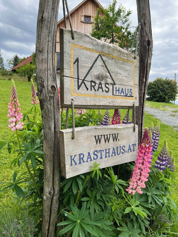 Ein Holzschild mit dem Schriftzug 'KRASTHAUS' und der Internetadresse 'WWW.KRASTHAUS.AT'.