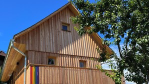 Una casa de fusta amb un balcó, una escala que condueix a l'entrada i vistes del paisatge circumdant.