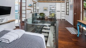 Een moderne hotelkamer met een bed, een televisie, een balkon en een trap naar een hoger niveau.