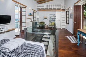 A modern hotel room with a bed, a TV, a balcony, and a staircase leading to an upper level. - Kito Transformed House - Sea View (Chania)