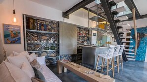 Een moderne woonkamer met een bank, een salontafel, en een keukenhoek met een bar en stoelen.