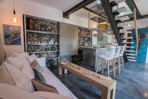 Una sala de estar moderna con un sofá, una mesa de centro y una cocina con barra y sillas.