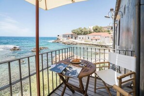A balcony with a table, a chair, and a view of the sea and buildings. - Kito Transformed House - Sea View (Chania)