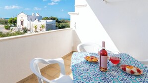 Ein Balkon mit Tisch für zwei Personen, einer Flasche Rotwein und einem Weinglas.