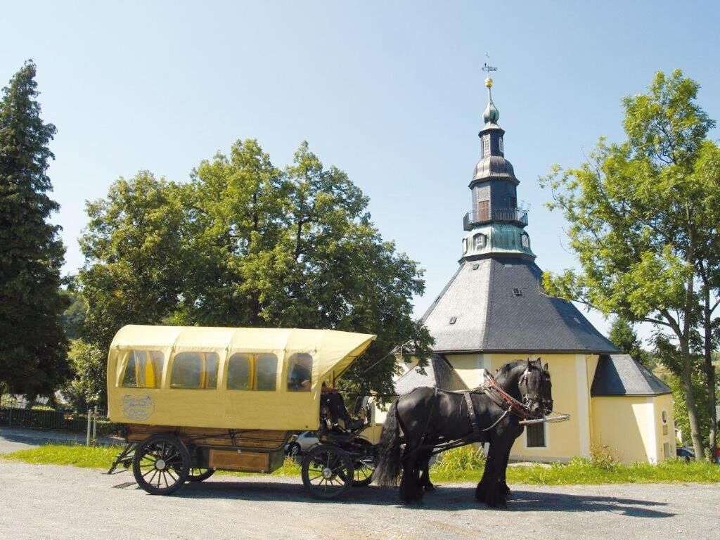 A horse-drawn carriage parked in front of a building with a tower.