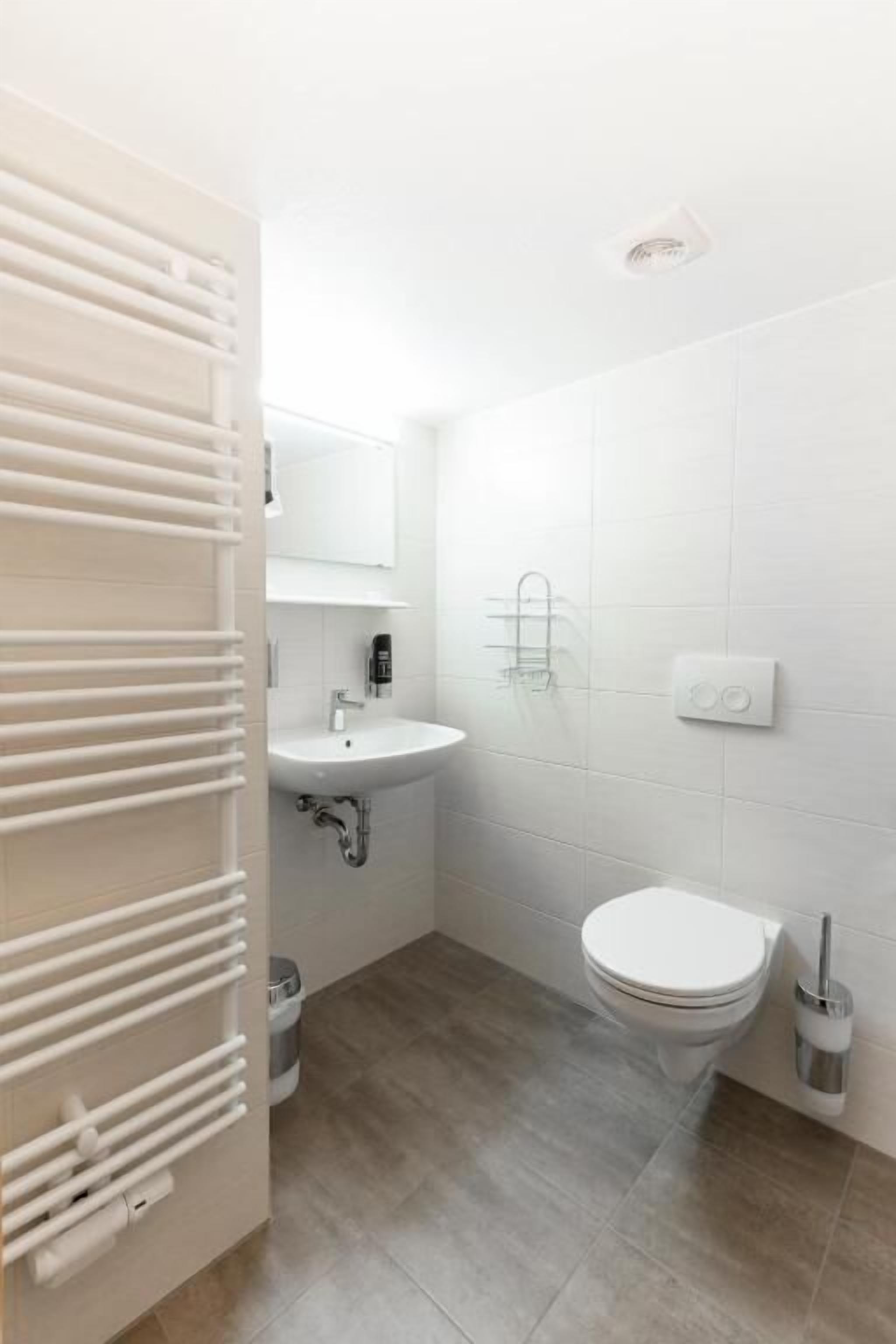 A small, modern bathroom with a toilet, sink, and towel rack.