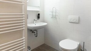 Un baño pequeño y moderno con inodoro, lavabo y perchero para toallas.