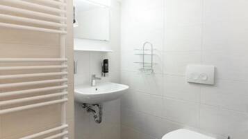 A small, modern bathroom with a toilet, sink, and towel rack.