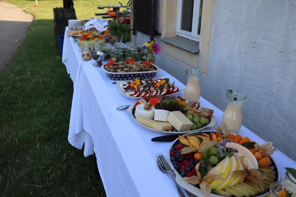 A table set outdoors with various food items and drinks.