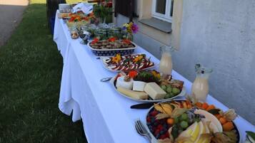 A table set outdoors with various food items and drinks.
