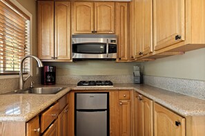 Una cocina con armarios de madera, electrodomésticos de acero inoxidable, encimera de granito y lavavajillas integrado.