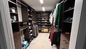 Ein begehbarer Kleiderschrank mit Regalen, Schubladen und Kleiderstangen.