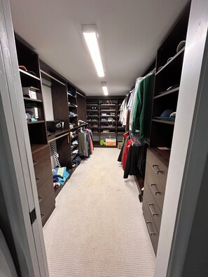 Een inloopkast met planken, lades en kledingroede voor kleding en schoenen.